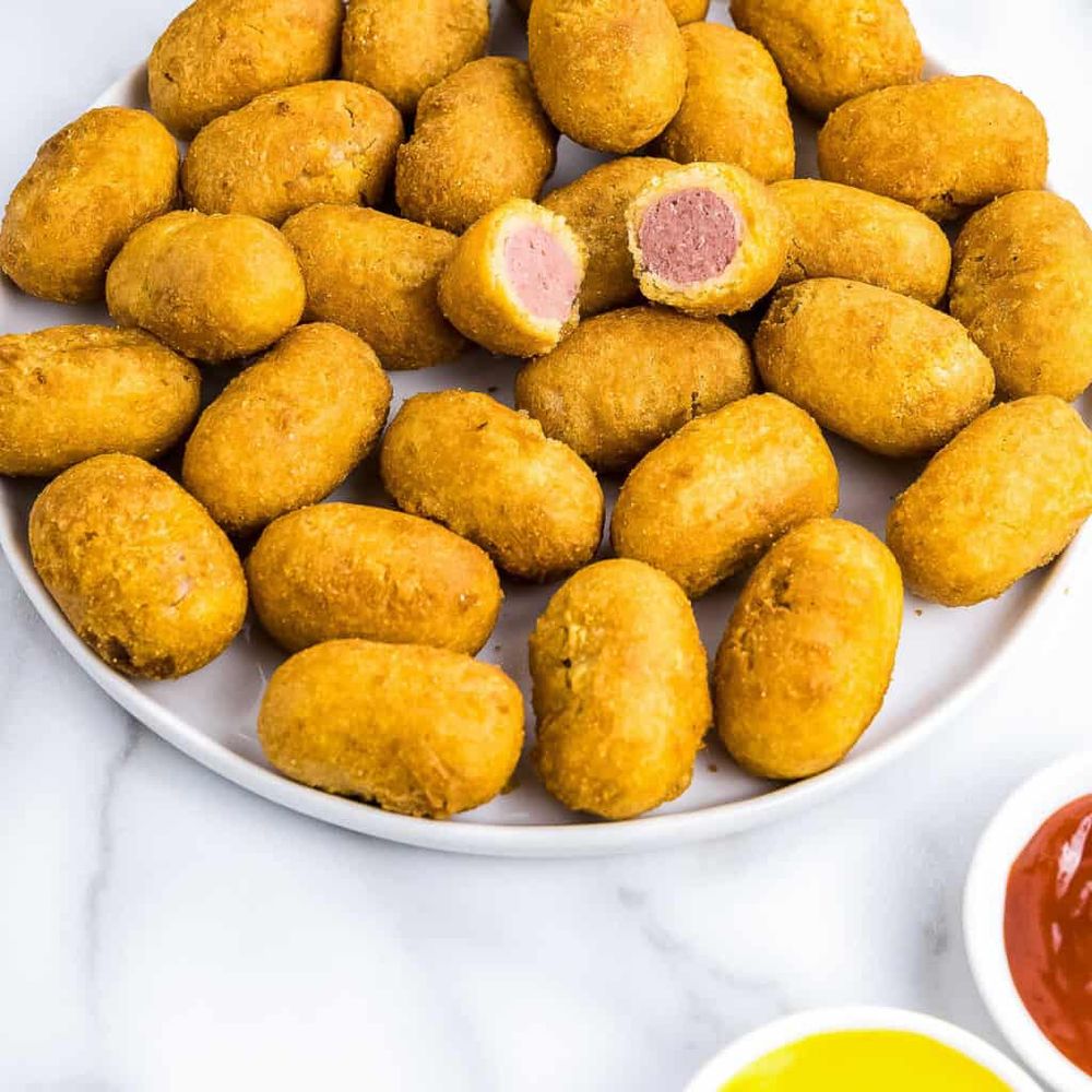 A picture of mini corndogs, with ketchup and mustard for dipping just out of frame