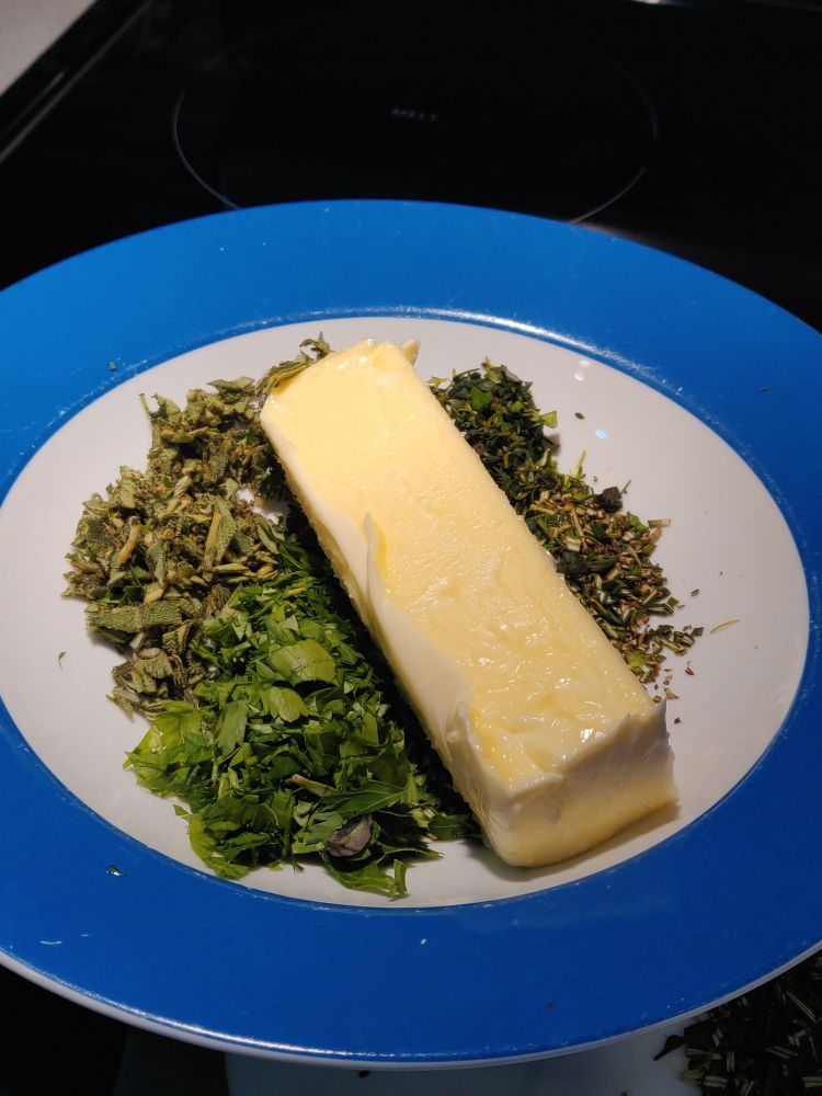 softened stick of butter laying on a bed of herbs