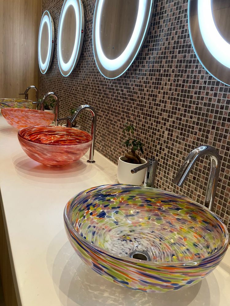 沖縄のお手洗いの、洗面ボウルが琉球ガラス(?)と女優さん鏡でお洒落の図