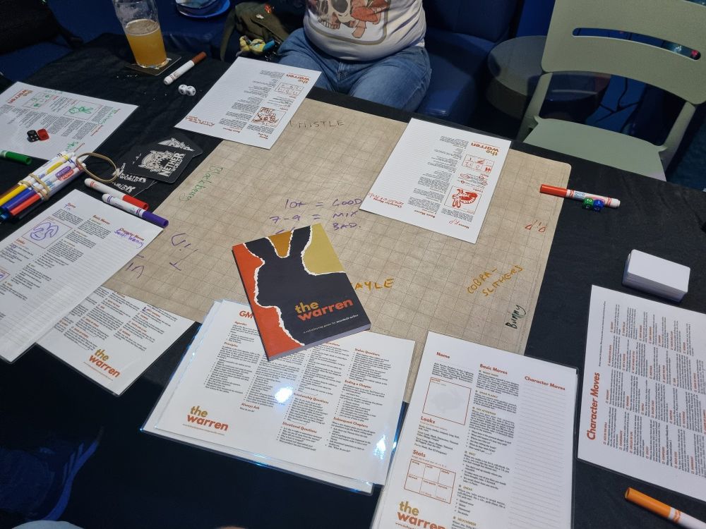 An RPG table with the game The Warren and some player sheets on it. At Netherworld Bar and Arcade in Brisbane Australia. 