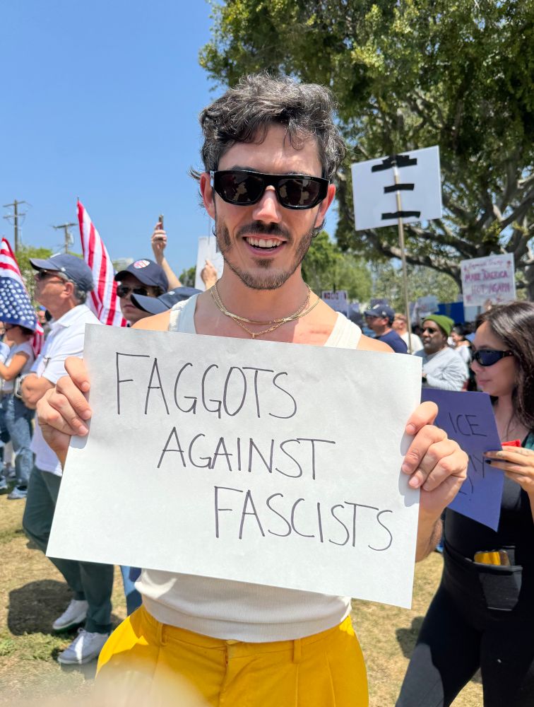 Protestor holding “Faggots against fascists” sign 