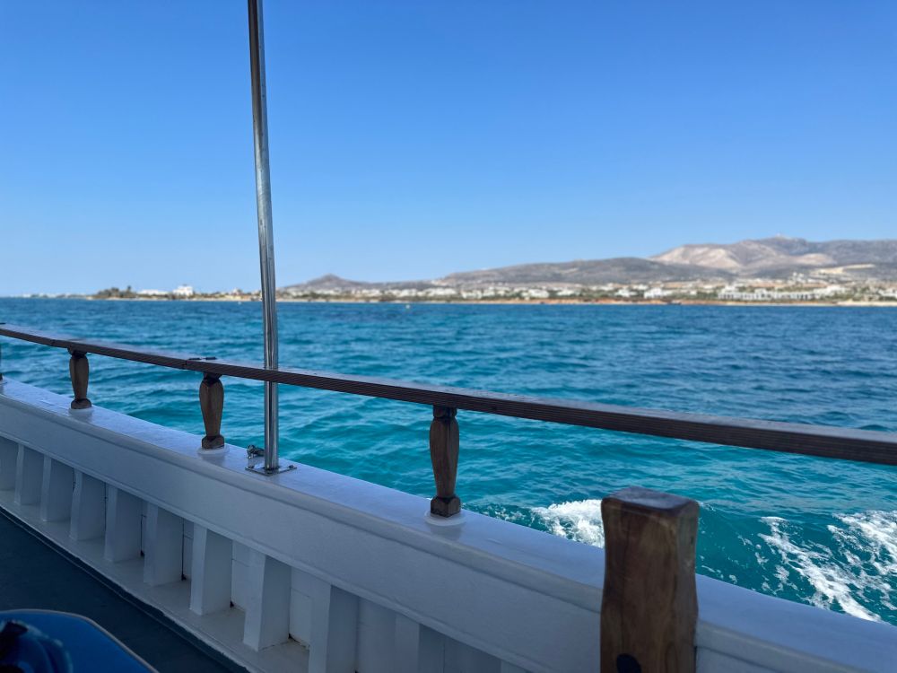 View from a boat of a coastline with white buildings and a clear blue sky