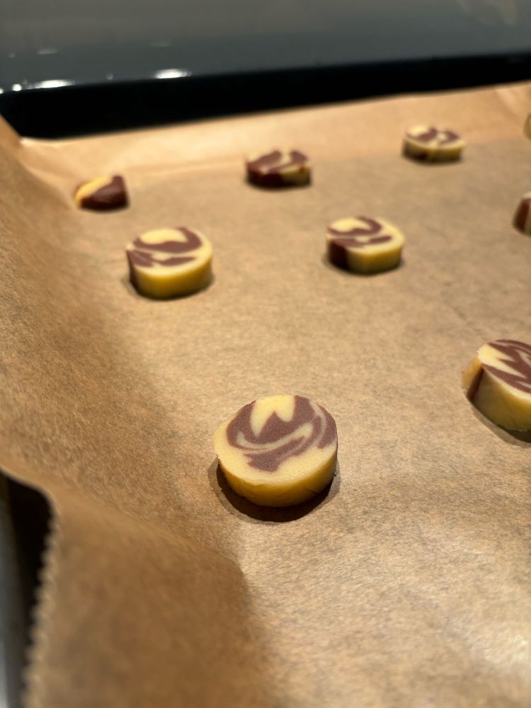 rohe keksteig scheibchen auf backpapier. schoko und vanille marmoriert.