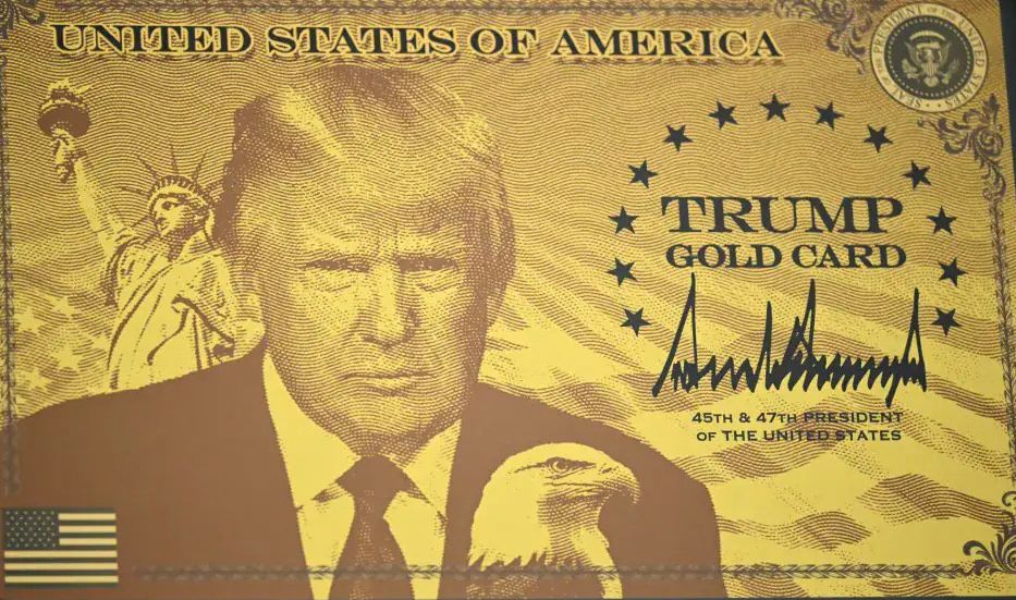 A gold-colored novelty card styled like an official document, featuring a central etched portrait of Donald Trump in a suit and tie, gazing seriously forward, with a bald eagle perched on his right shoulder and the Statue of Liberty visible in the background. The card has a golden background with ornate borders and stars. At the top, bold text reads "UNITED STATES OF AMERICA." In the center, it says "TRUMP GOLD CARD" surrounded by stars. Below the portrait is a signature resembling "Donald J. Trump" and text stating "45th & 47th President of the United States." A small American flag appears in the bottom left corner.