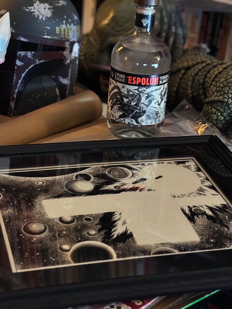 A photo of a framed Virgil Finlay space illustration next to a bottle of Espolon tequila