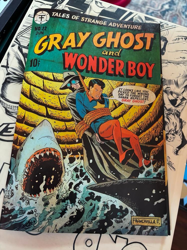 A faux cover with the gray ghost and wonder boy tied to a rope and hanging over a pool with sharks. Wonder boy says “it looks like you picked the wrong day to forget the shark repellent, gray ghost!”