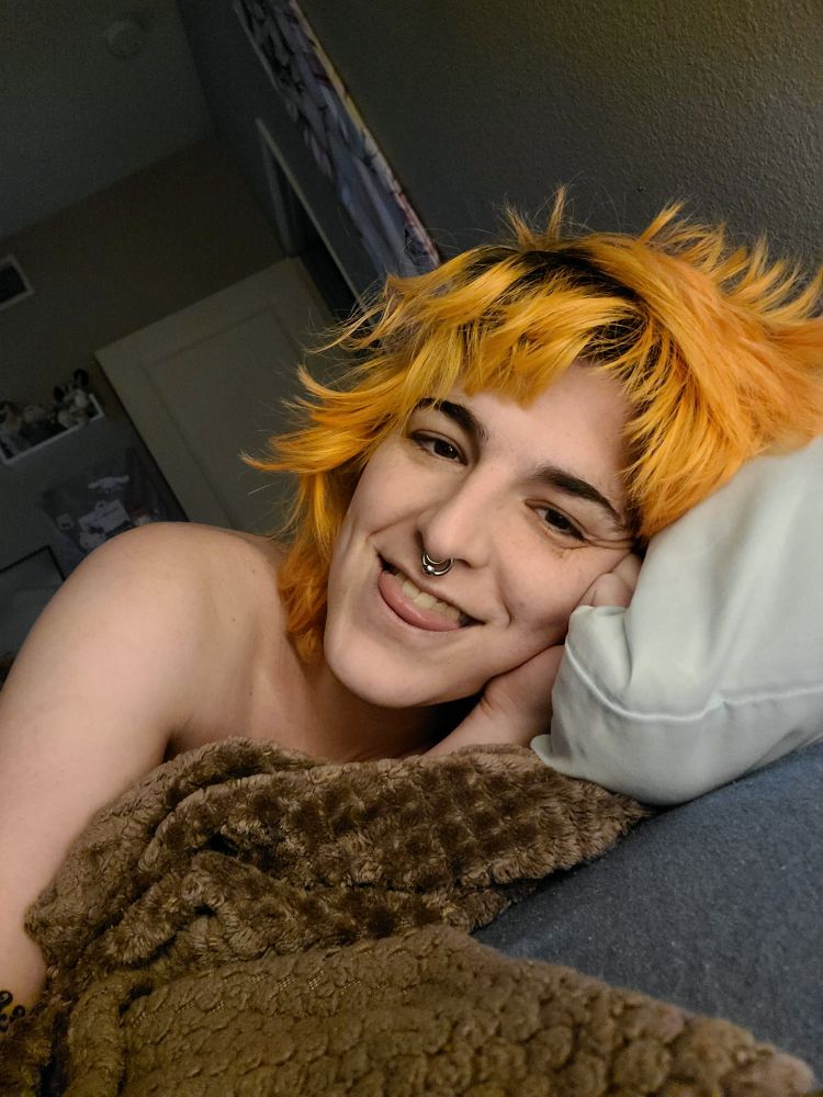 sleepy Bailey in bed, smiling with her tongue sticking out a bit