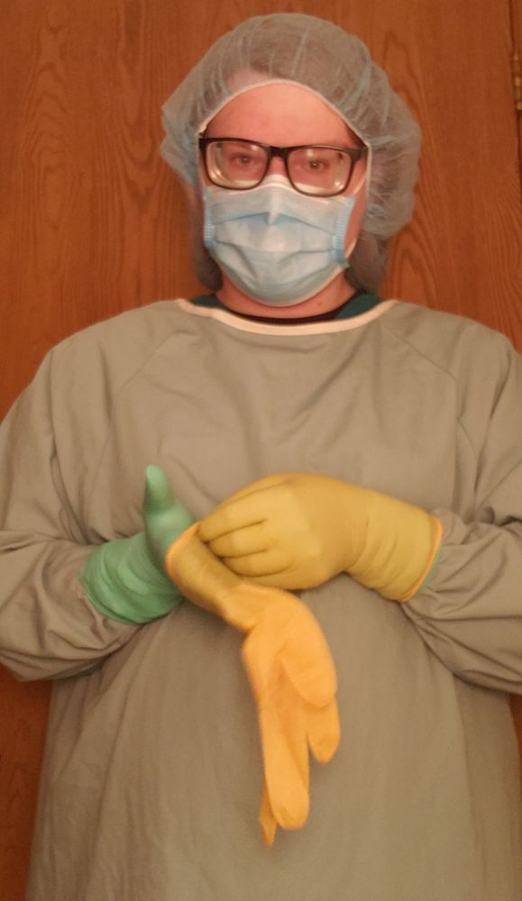 I'm standing in surgical gown, cap and mask, slipping a second glove over my right hand