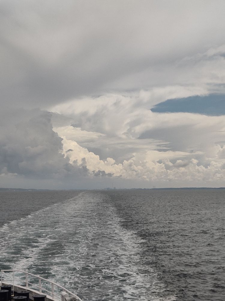 The wake of a ferry with a cloudscape overhead