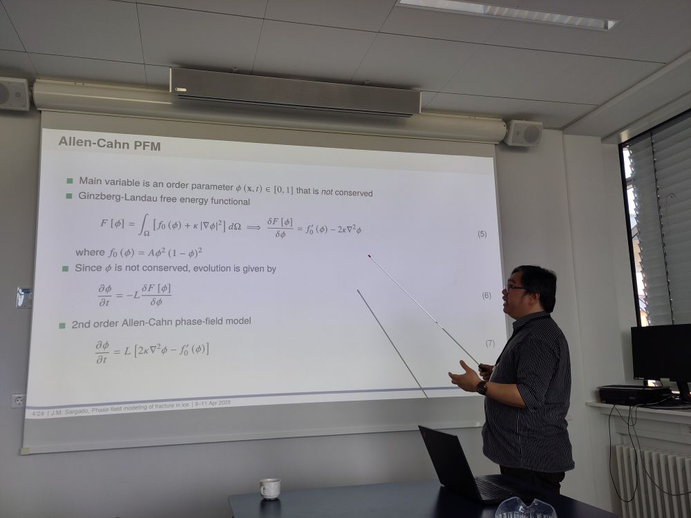 Man standing in front of a screen with equations on it headed Allen-Cahn PFM