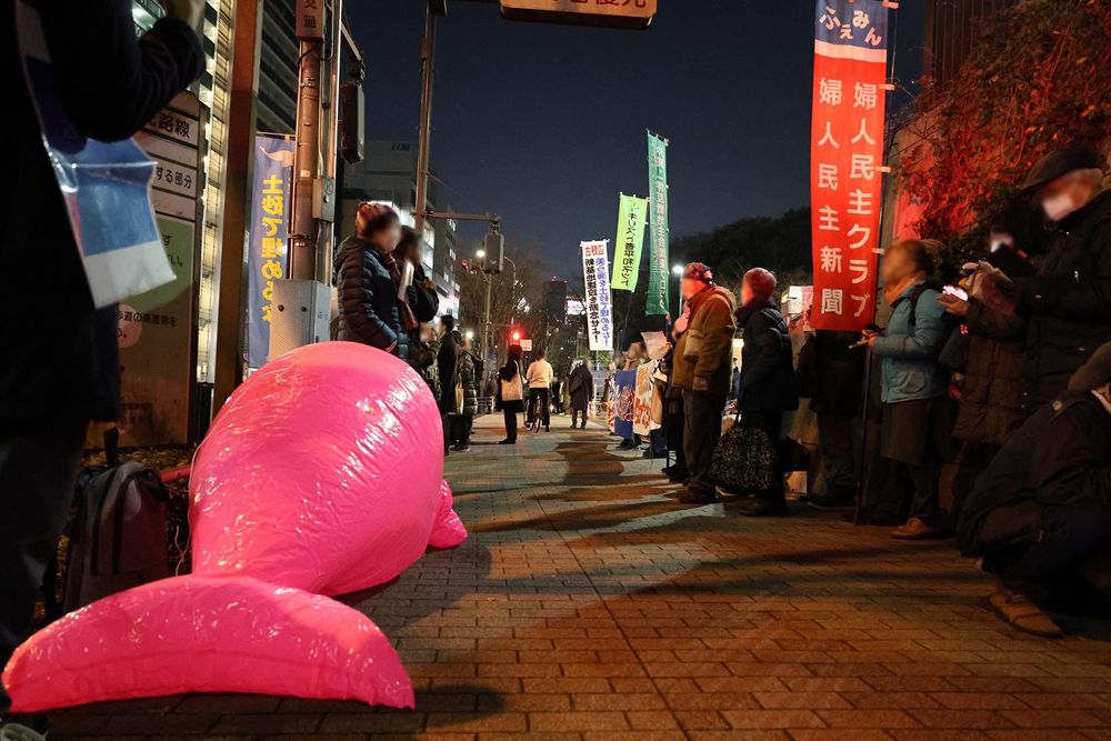防衛省抗議・申し入れ行動の当日の様子を写した写真。
防衛省正門前で、抗議文を防衛省側に手交する主催者や、「沖縄・辺野古の海を埋め立てるな」の横断幕や「美ら海を土砂で埋めるな！新基地建設を断念せよ！」といった幟旗がみえる。
