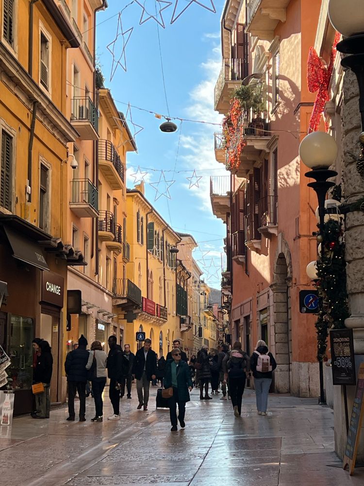 Photo of an street of verona old town market with some people and shops