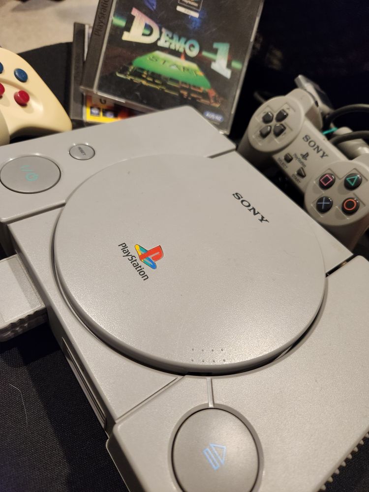 a photo of a PS1 with a version of its pack in demo disc, the DEMO 1 pictured with a couple of controllers