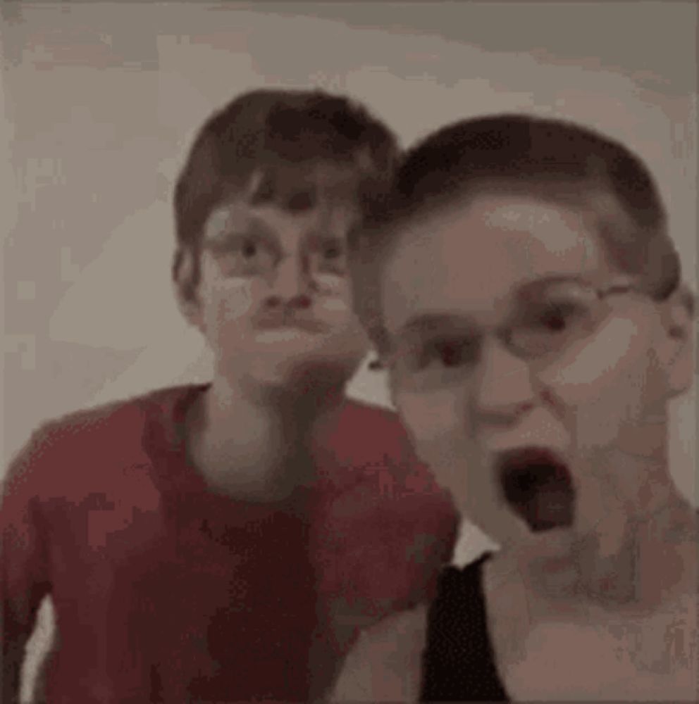 two young boys wearing glasses are standing next to each other making funny faces .