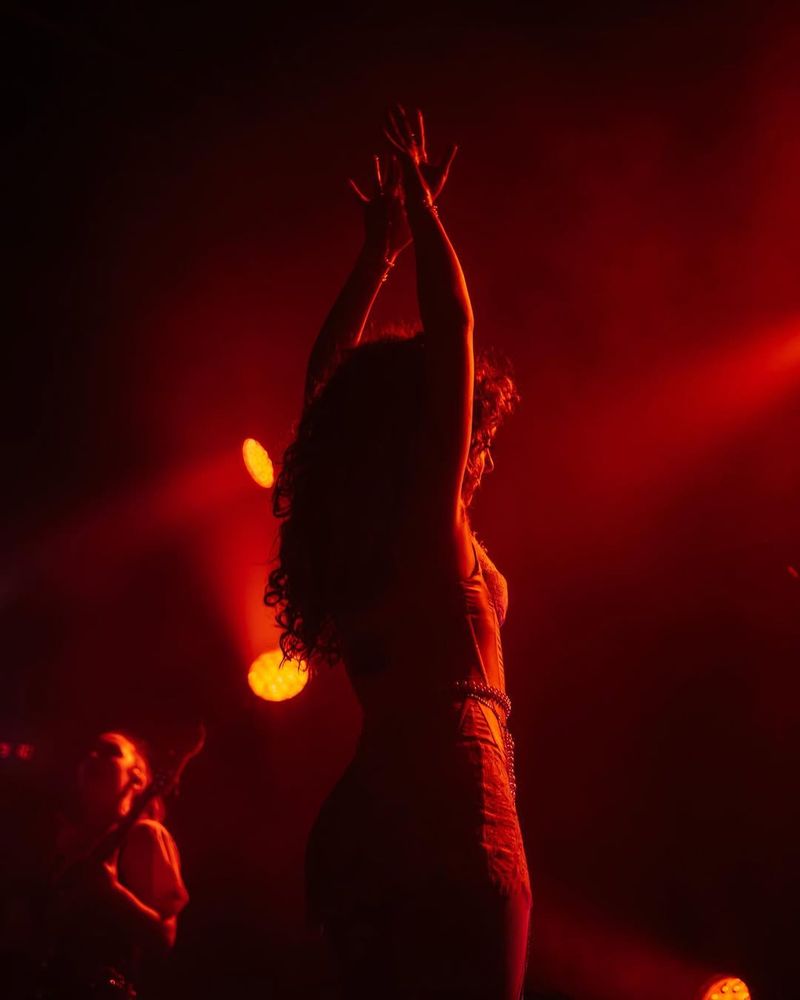 Chappell Roan viewed from behind under red spotlights with arms raised above her head. Photo @jadelynnphoto.