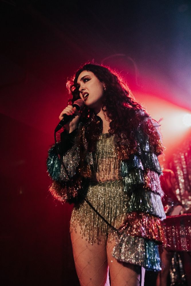 Chappell Roan performing in a spangled silver outfit with multicolored fringed sleeves. Photo DAPHNE STUBBLEFIELD.