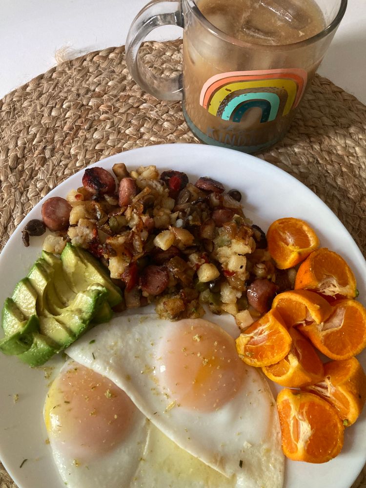 White dish, two large steam-topped eggs, 2 cutie orange mandarins quartered, green avo slices, hash of cubes potatoes onion bell pepper mushroom mini sausages. Delish!