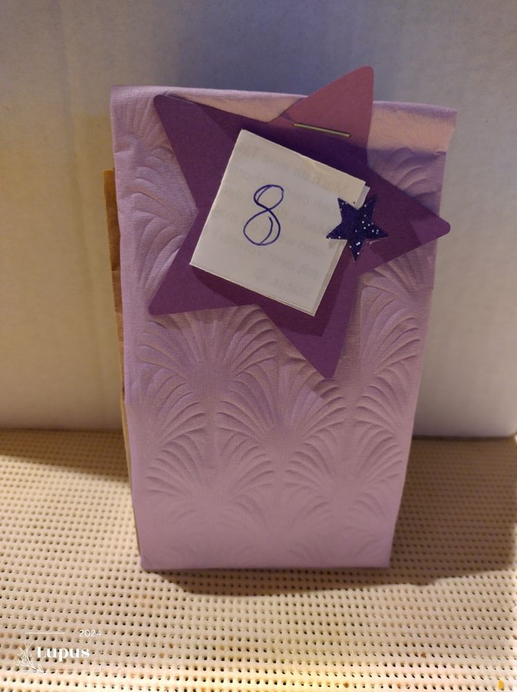 Eine violettfarbene Verpackung mit einem violettfarbenen Stern. Ein Papier mit der Challenge darauf ist die acht geschrieben.

