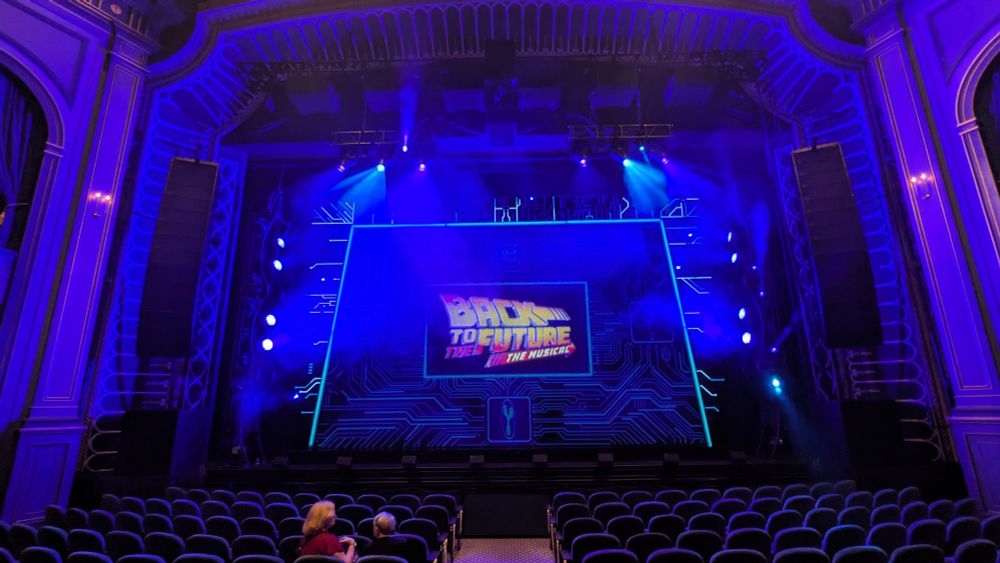 A stage, with the curtain advertising the show as Back To The Future: The Musical