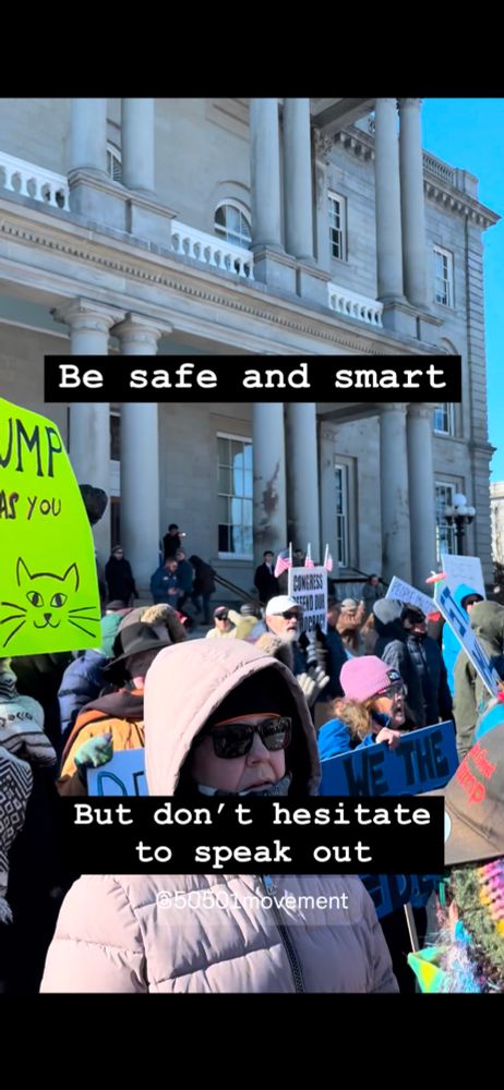 Protestors holding signs in front of the NH State House steps