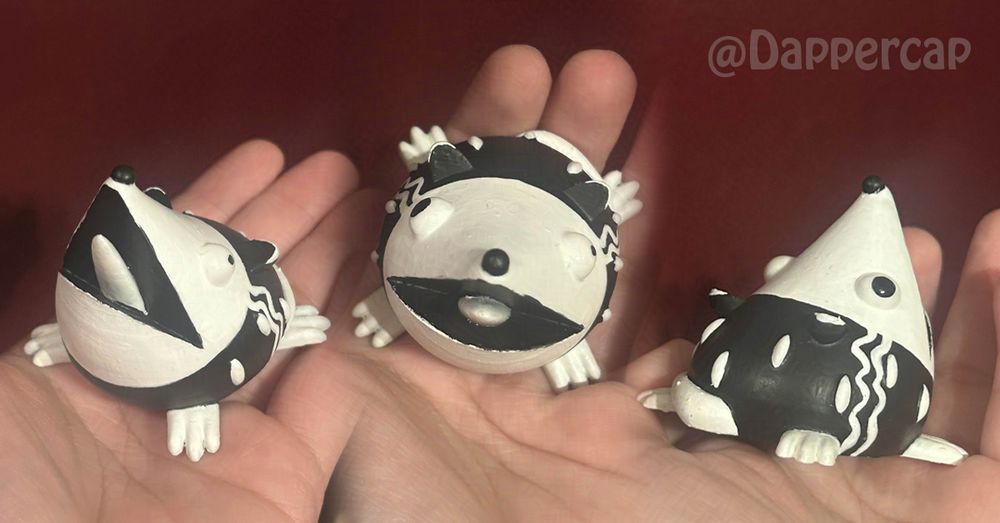 A collage of three images of a stylized, screaming possum figurine. It's fully black and white, with white wiggly stripes going down its body, reminiscent of the hairstyle of The Bride of Frankenstein.