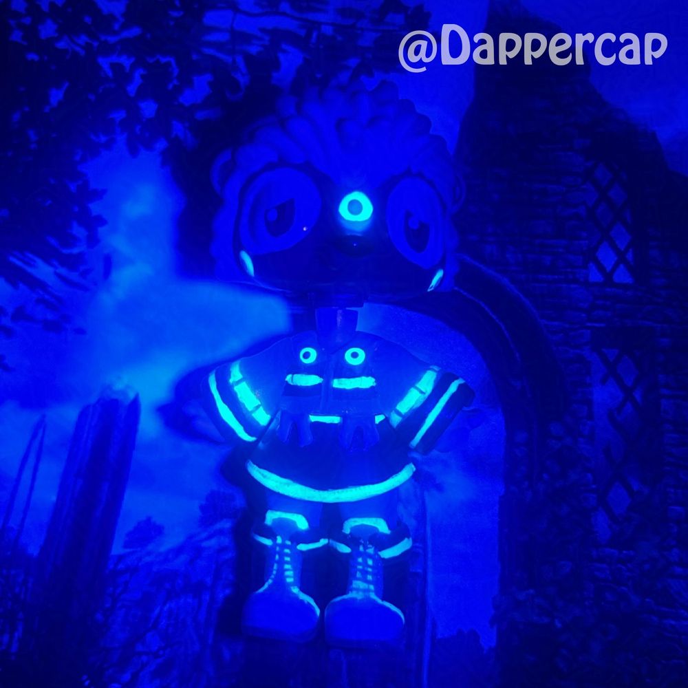 A blacklight picture of a hand-painted hybrid mini doll inspired by Silver the Hedgehog, floating in some overgrown ruins.

Head came from a Littlest Pet Shop Hedgehog and the body/outfit came from a Yummiland Doll.