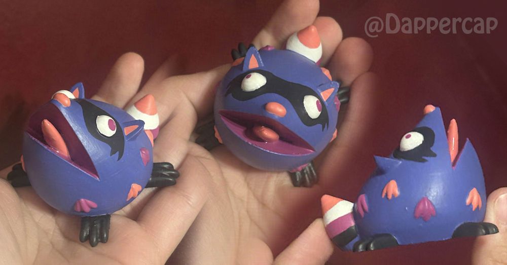 A collage of three images of a small stylized figurine of a screaming raccoon. Its color scheme is borrowed from the genderfluid pride flag, with a purply-blue body, pink and purple accents, and dark grey mask and feet. Its tail stripes imitate the stripes of the flag.