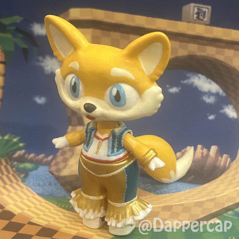 A picture of a hand-painted custom hybrid doll inspired by Tails the fox, standing in Green Hill Zone.

Head came from a Littlest Pet Shop Bootleg, body/clothes came from Lol OMG Surprise dolls, and the tails were 3D modeled and printed by me.