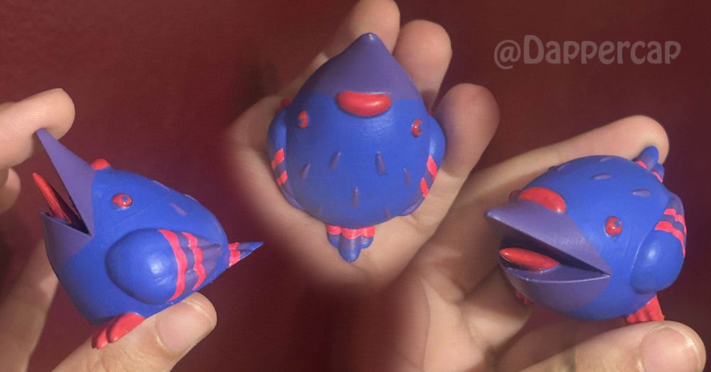 A small stylized figurine of a screaming pigeon. It's color scheme is borrowed from he Bisexual Pride Flag, with a blue body, purple beak and feathers, and pink accents like the eyes, feet, tongue, and stripes.