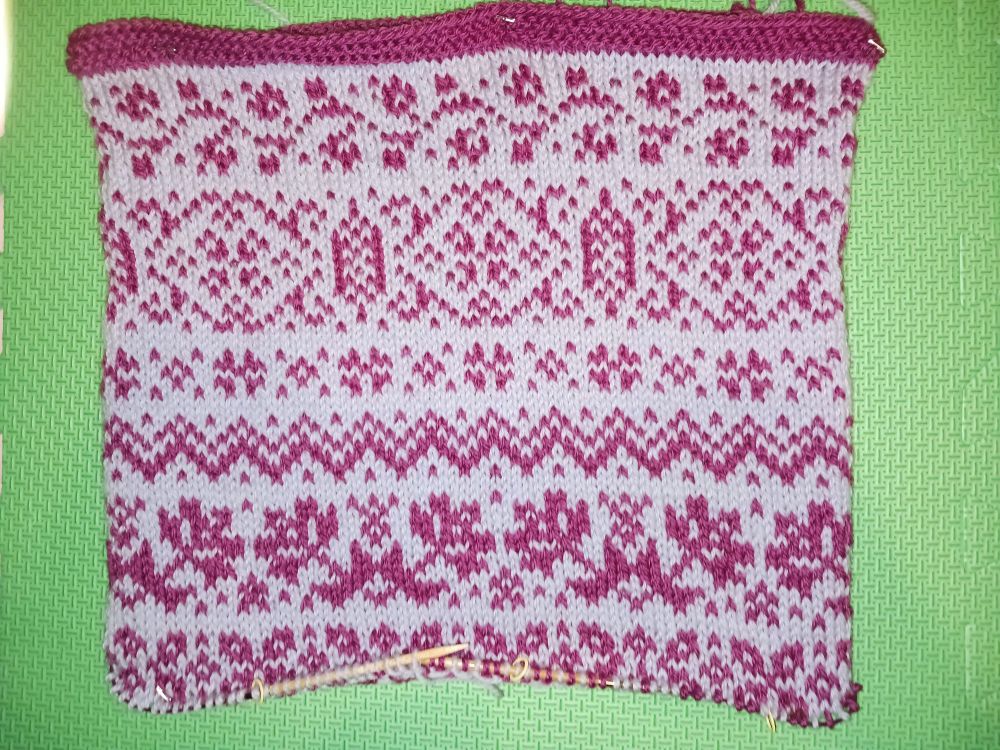 Unfinished knitted bag done in raspberry and gray colorwork. There are 6 different motifs of varying widths.