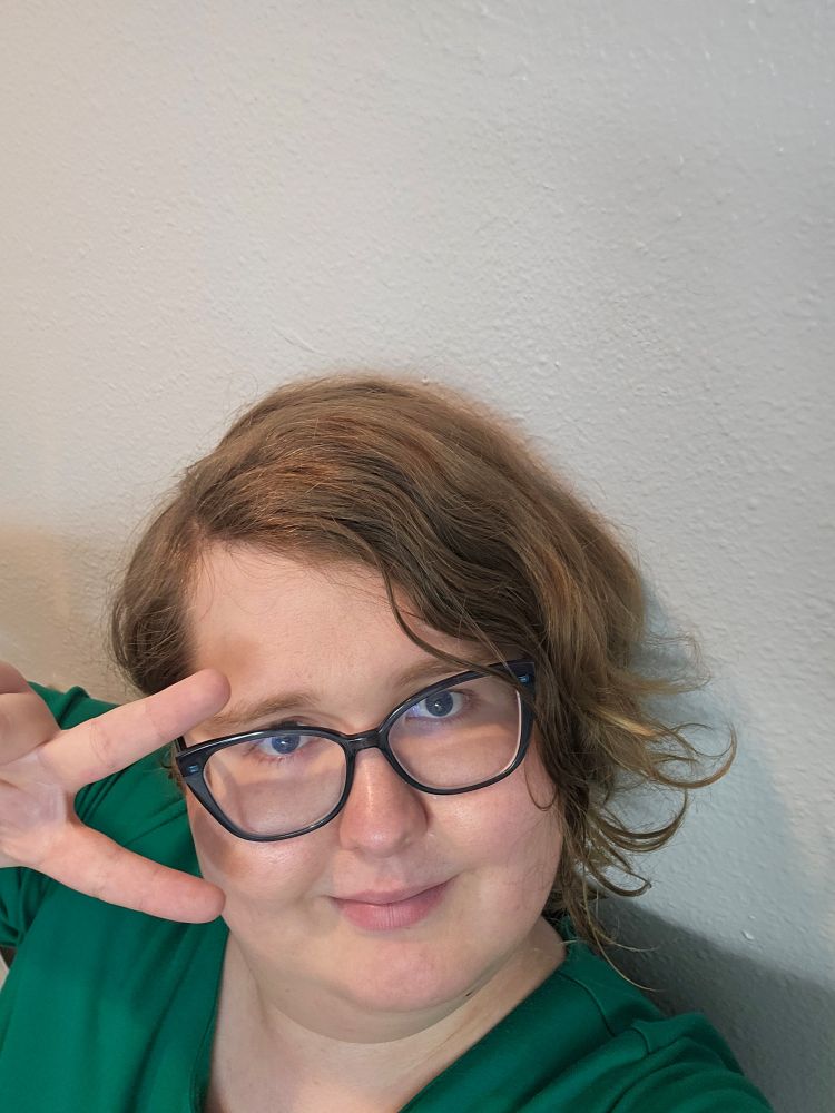 Me, today. I'm wearing a green dress and my hair is still in it's undercut, but has curled significantly. I'm replicating the pose from the DMGMC concert albeit from a much higher camera angle.