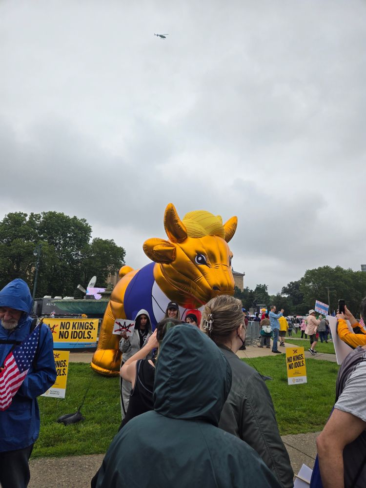An inflatable golden calf wearing a blue suit jacket, white shirt, red tie, and the characteristic comb over of Donald Drumpf.