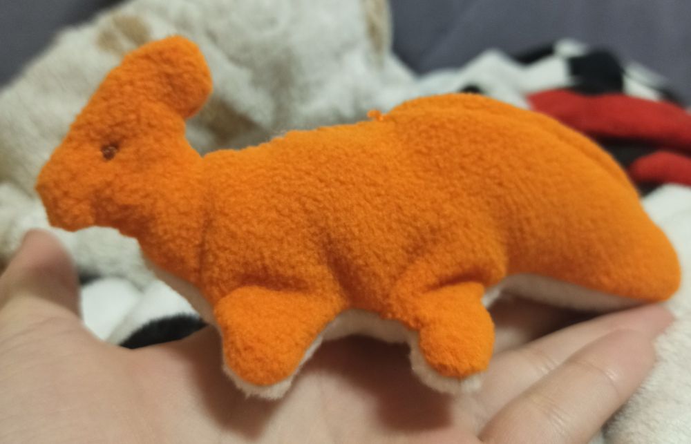 a photograph of an orange fleece Parasaurolophus; it doesn't have much details besides embroidered brown eyes 