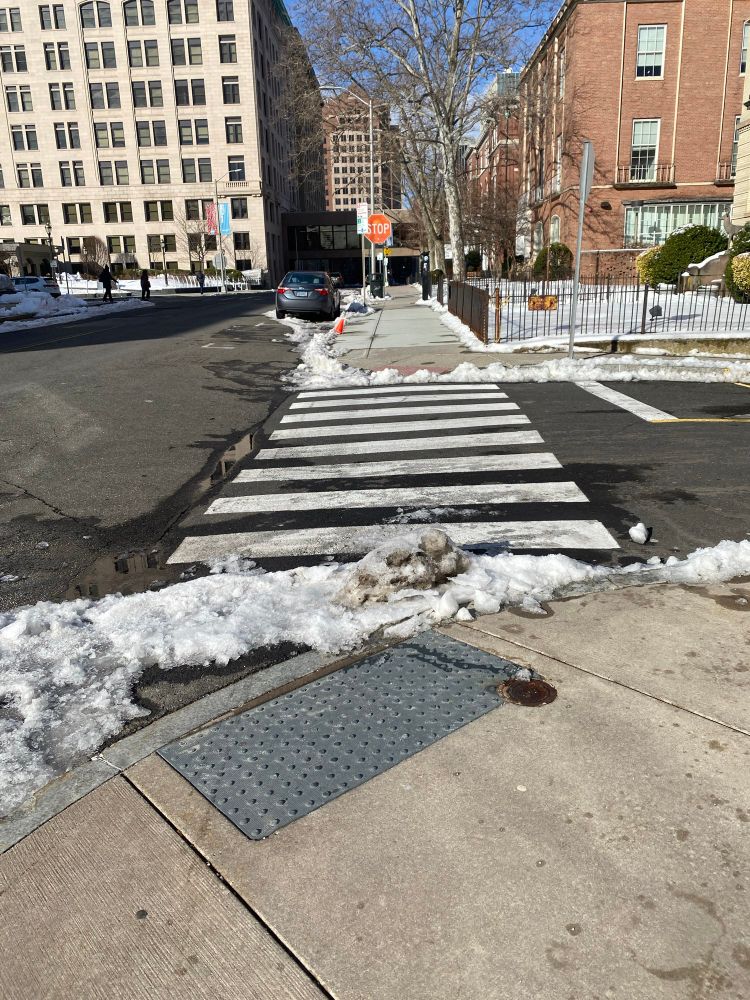 After snowstorms the street and sidewalk are clear but the crosswalk has snow and ice at the curb cut. 