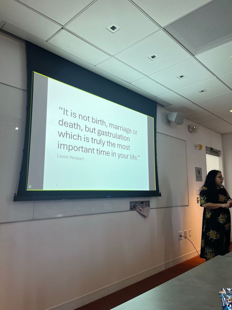 Dr. Gloria Ligunas standing next to a slide with the Lewis Wolpert quote “It is not birth, marriage, or death, but gastrulation which is truly the most important time of your life.”