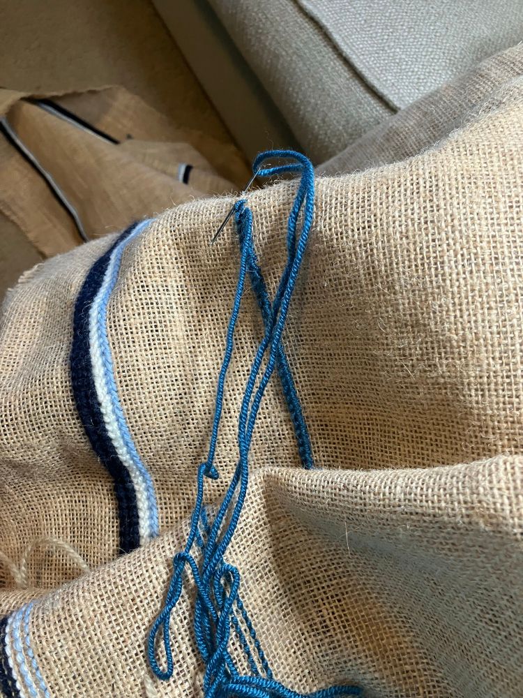 Picture of a long bunched up burlap runner with rows of stitches along the sides