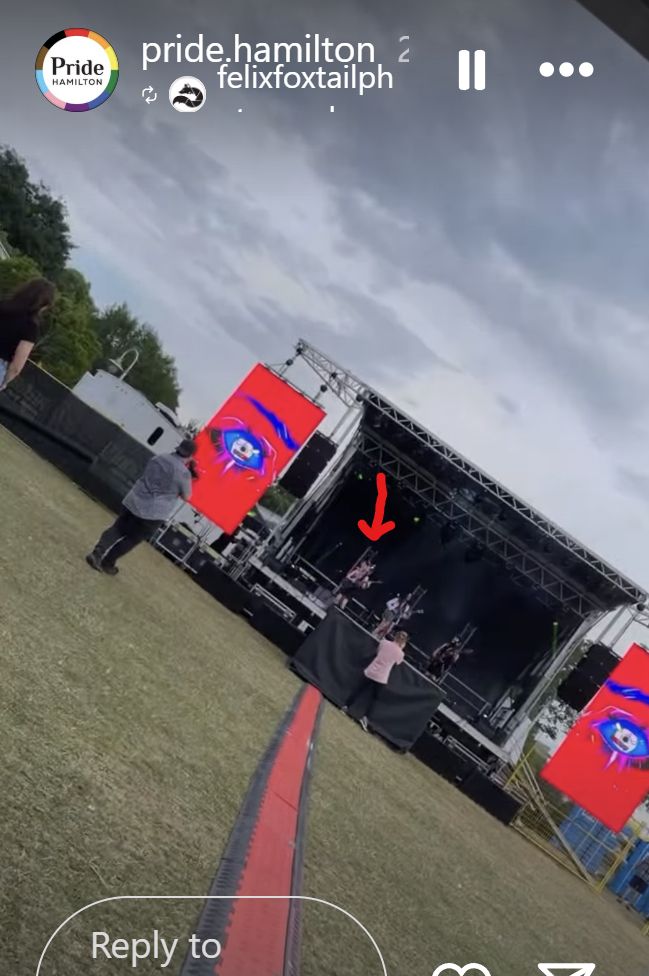 monstrosa band playing at pride hamilton. the stage is far away and there are eyes on either side from their 2nd album artwork