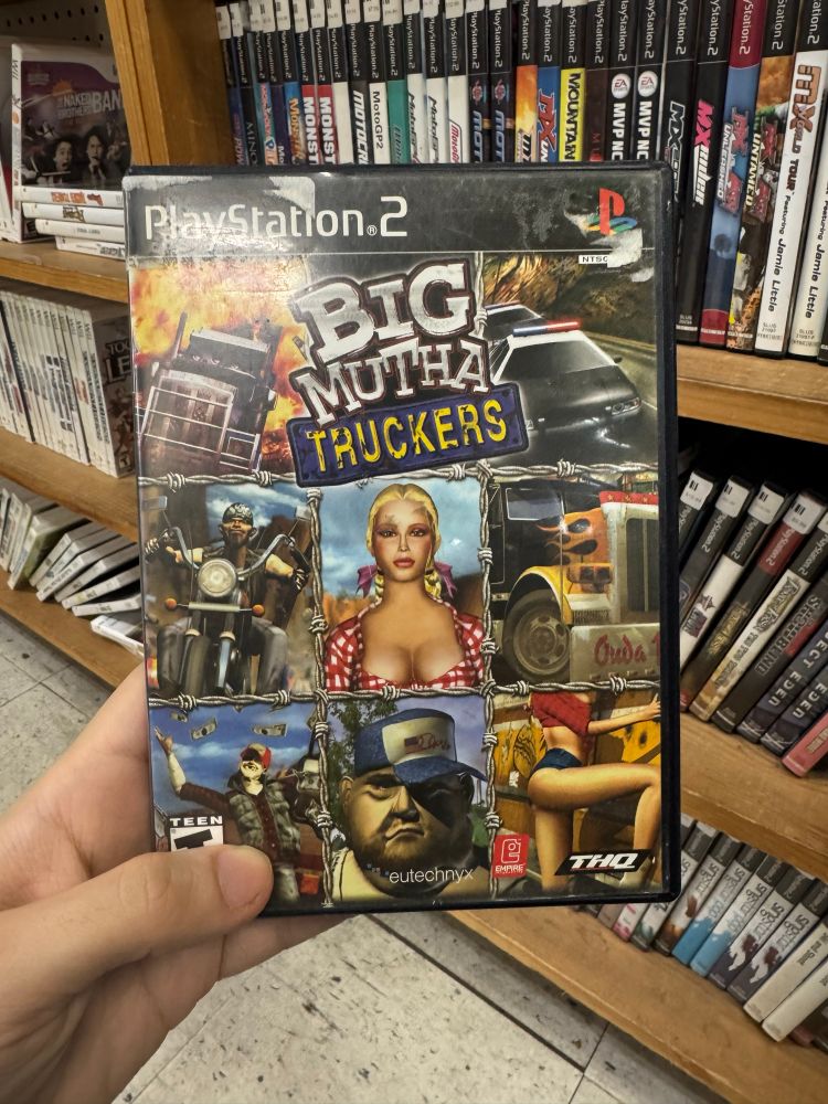 A hand holds the PS2 box for Big Mutha Truckas.