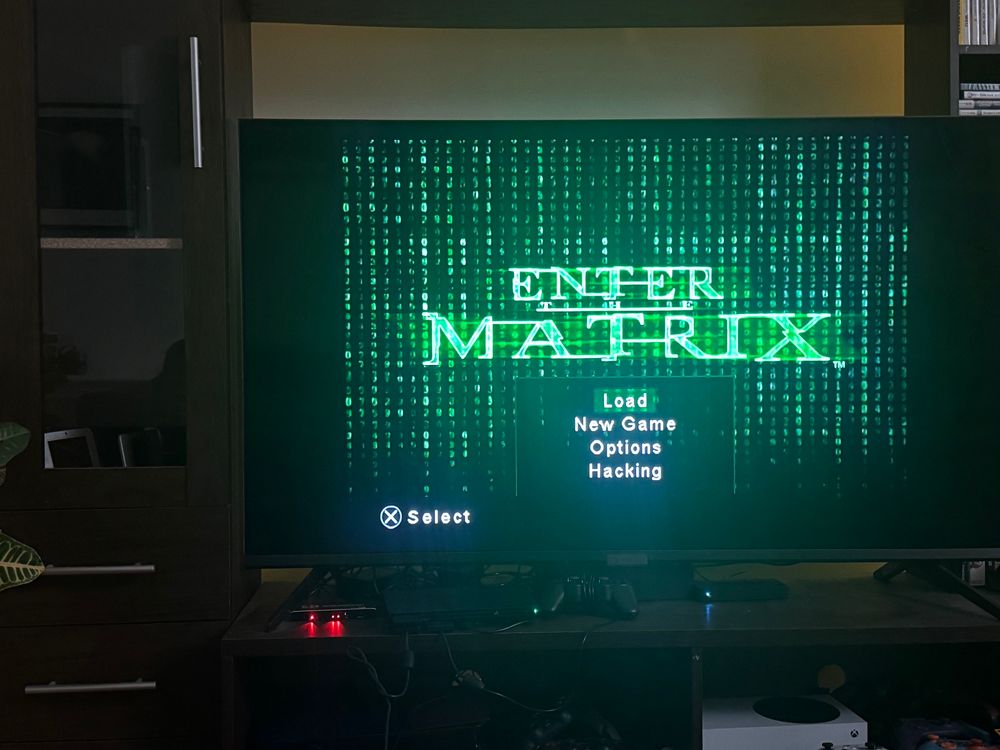 The opening menu screen for Enter the Matrix appears on a a TV screen.