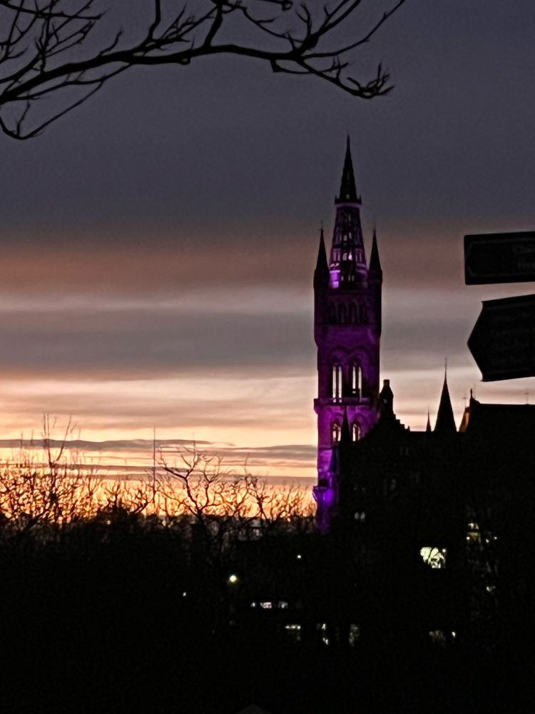Glasgow Uni Tower lit up in purple and the sun setting over Glasgow from Kelvingrove’s highest point. 
