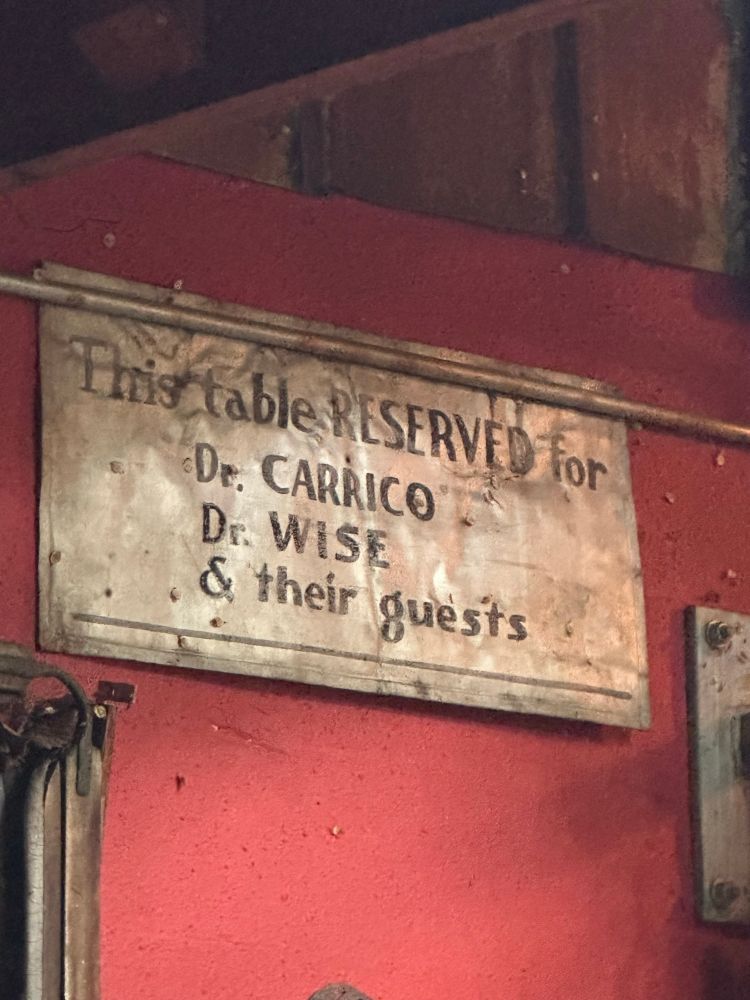 Sign says: This table RESERVED for • De. CARRICO Dr. WISE & their guests