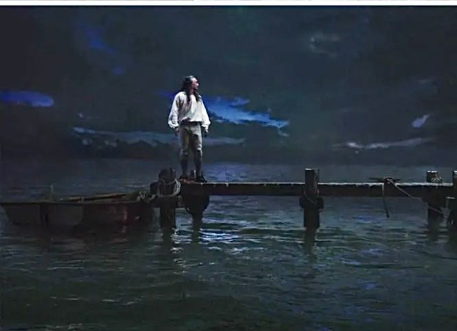 a person waits by the end of a dock in the moonlight. no one is coming
