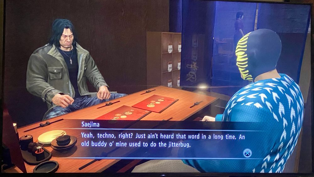 Saejima out for drinks with his masked wrestler Fighter Maker student saying “Yeah, techno, right? Just ain't heard that word in a long time. An old buddy o' mine used to do the jitterbug.”