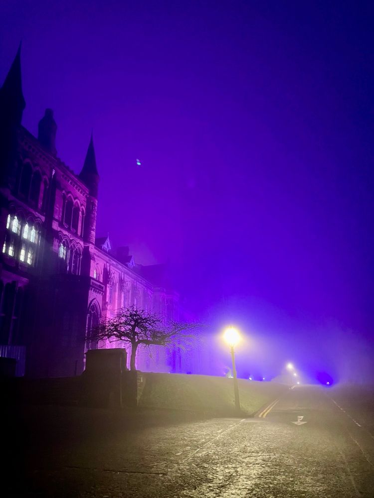 The university of Glasgow on a freezing foggy night. The fog is illuminated by the purple flood lighting, giving the imposing gothic building an otherworldly feeling 
