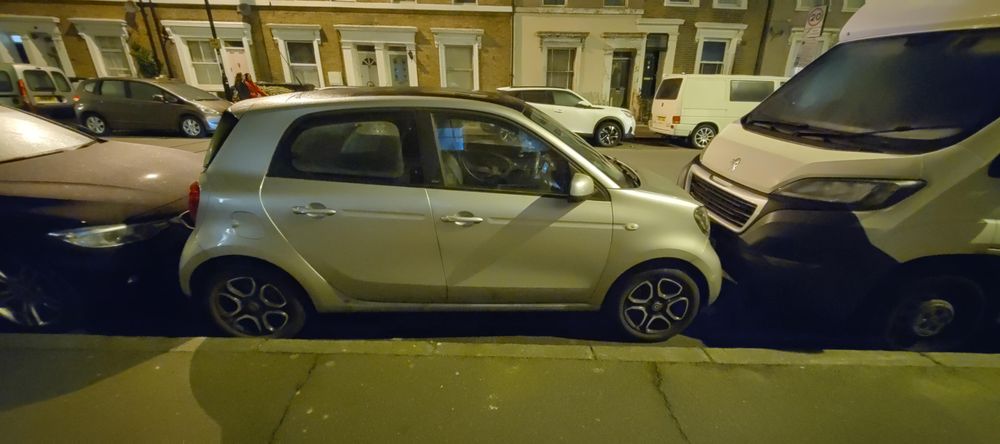 A Smart car parallel parked in a tight space.