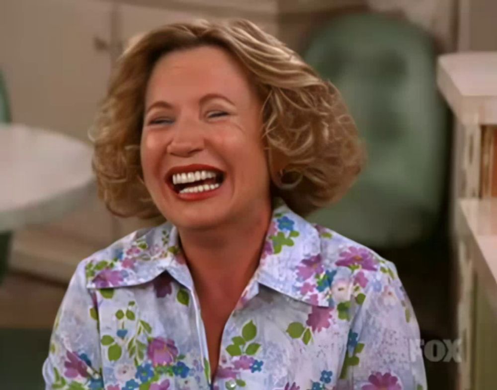 a woman in a floral shirt is laughing with the fox logo in the background