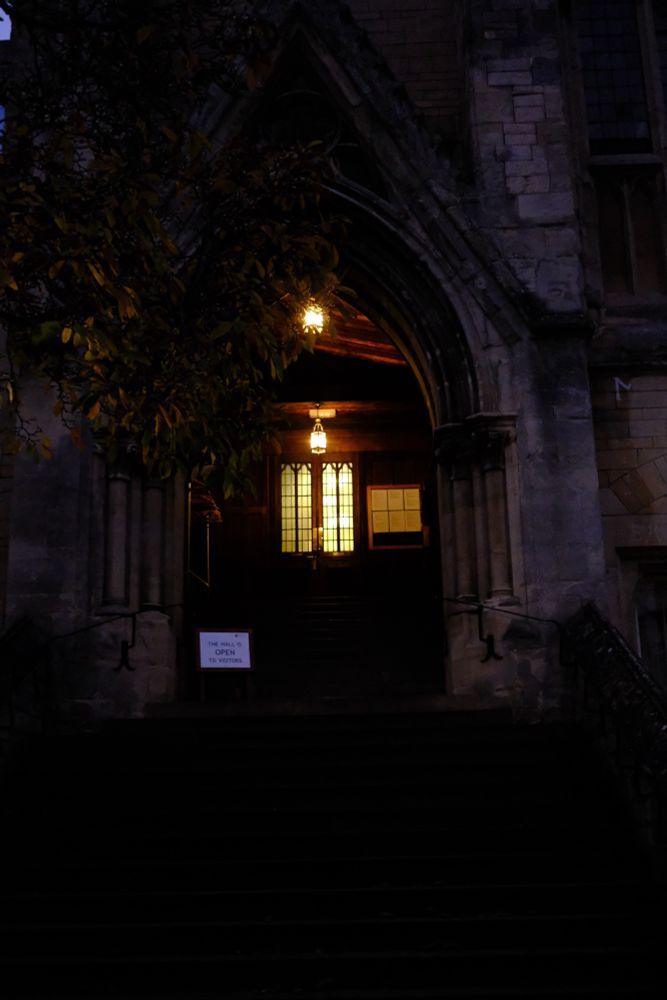 a dark photograph at twilight with two glowing lamps inside a gothic arch 