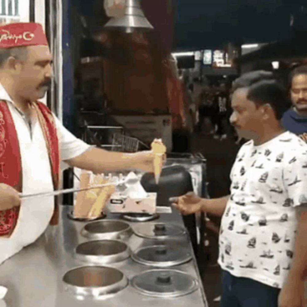 a man wearing a red hat is pouring ice cream into a cone .