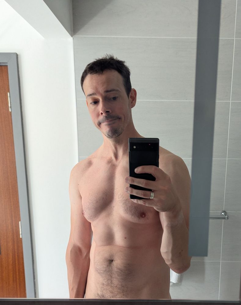 I am kinda defined and muscled and pulling an expression I am unsure of. If you could peek just over the mirror you would see my cock, but you can't so you won't