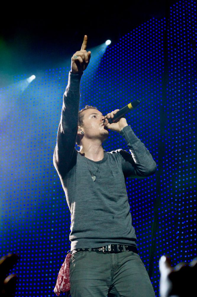 Chester Bennington of Linkin Park. One arm in the air, pointing his index finger to the sky, mic to his mouth.